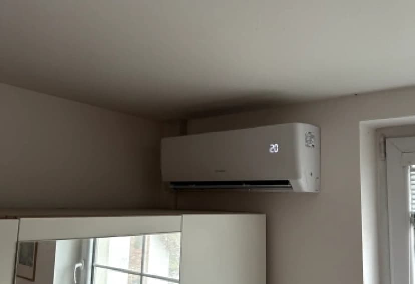 Nástěnná klimatizace Gree s displejem 20 °C v rohu obytné místnosti