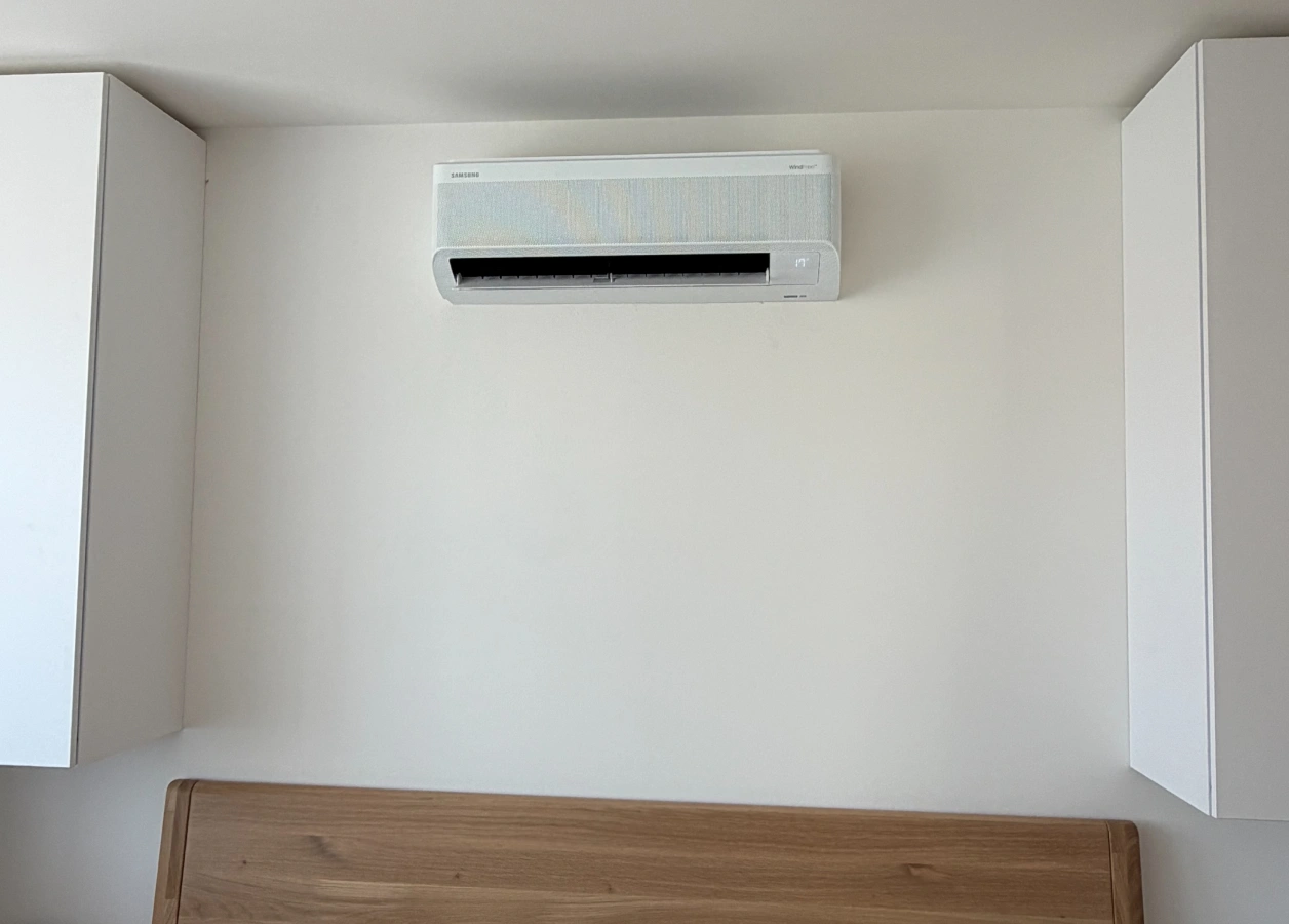 Vnitřní jednotka nástěnné klimatizace Samsung WindFree nad čelem postele v ložnici