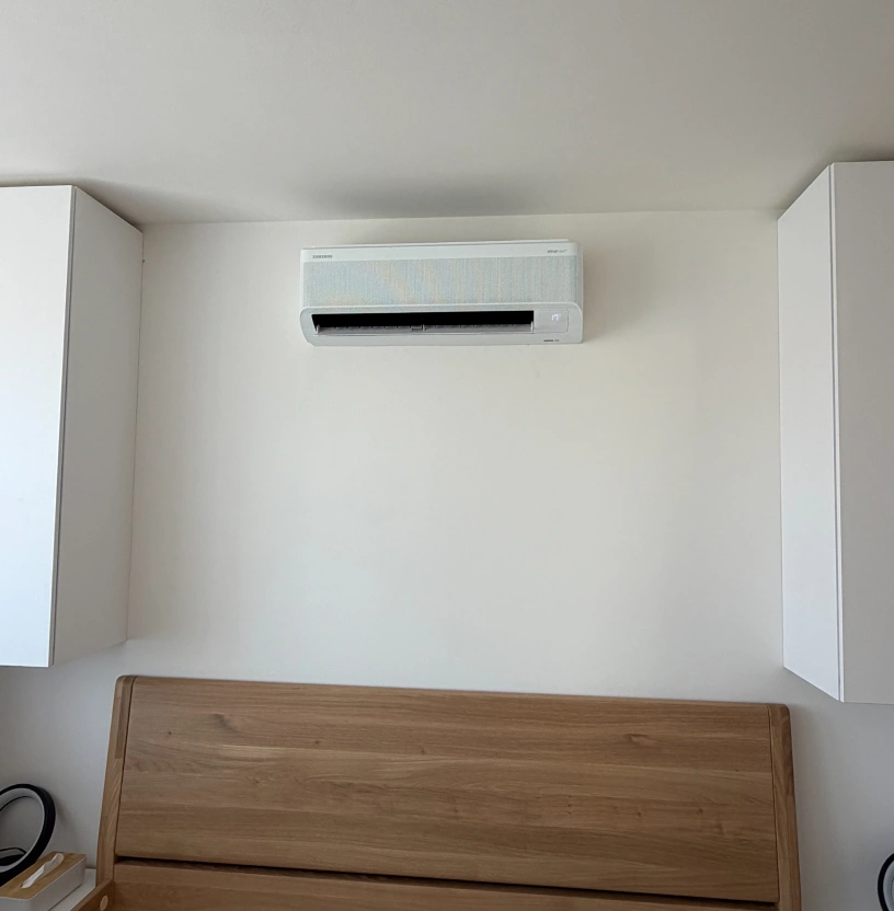 Nástěnná klimatizace Samsung WindFree nad čelem postele v ložnici bytu