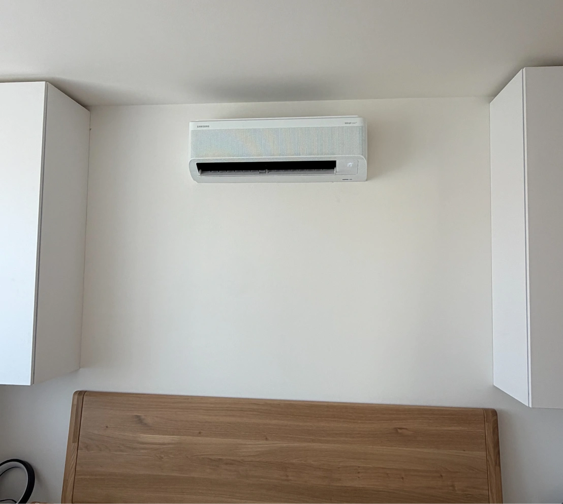 Bílá nástěnná klimatizační jednotka Samsung WindFree namontovaná mezi skříňkami