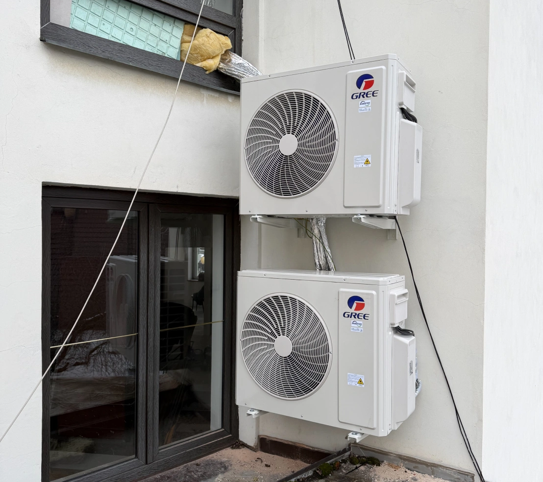 Dvě venkovní klimatizační jednotky Gree Inverter upevněné nad sebou na nástěnných konzolích
