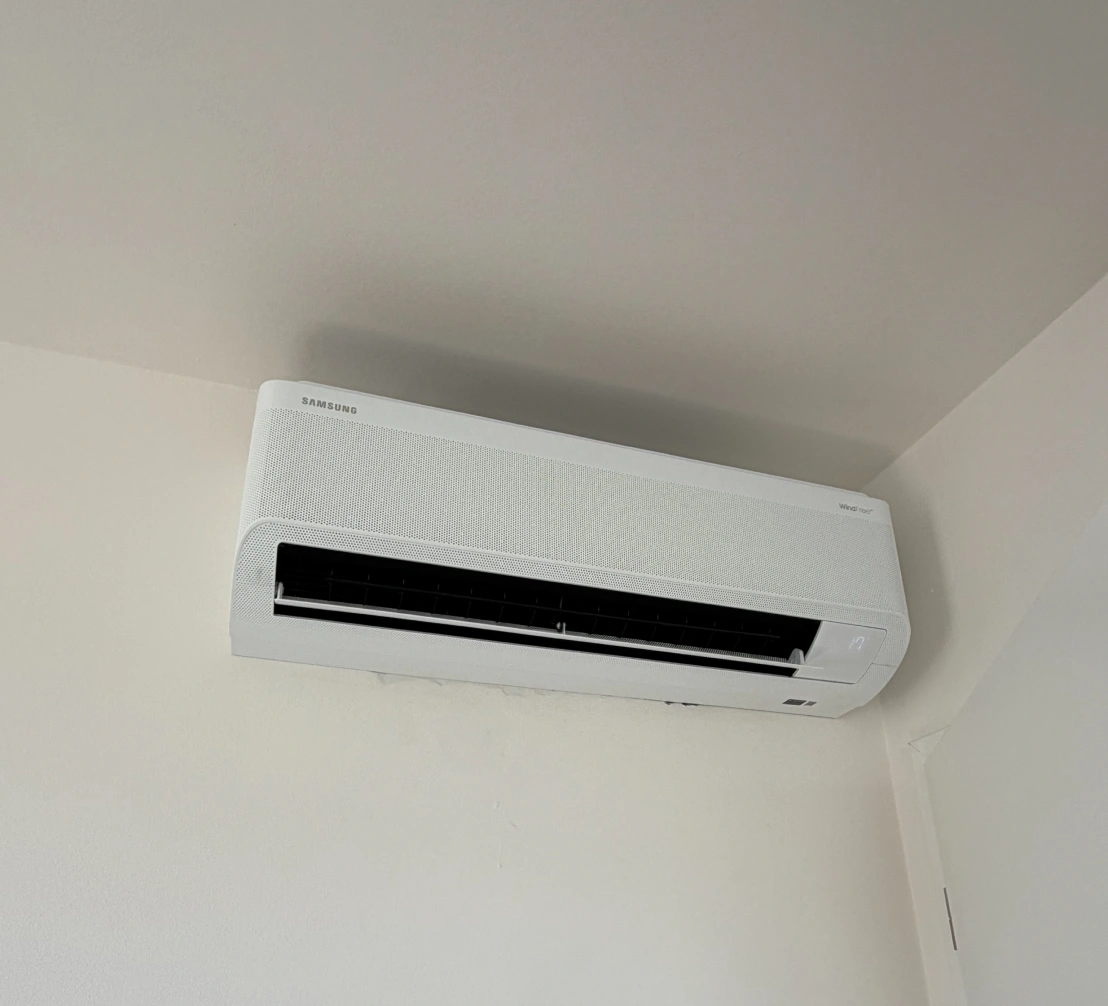 Bílá nástěnná klimatizace Samsung WindFree s tepelným čerpadlem v rohu místnosti