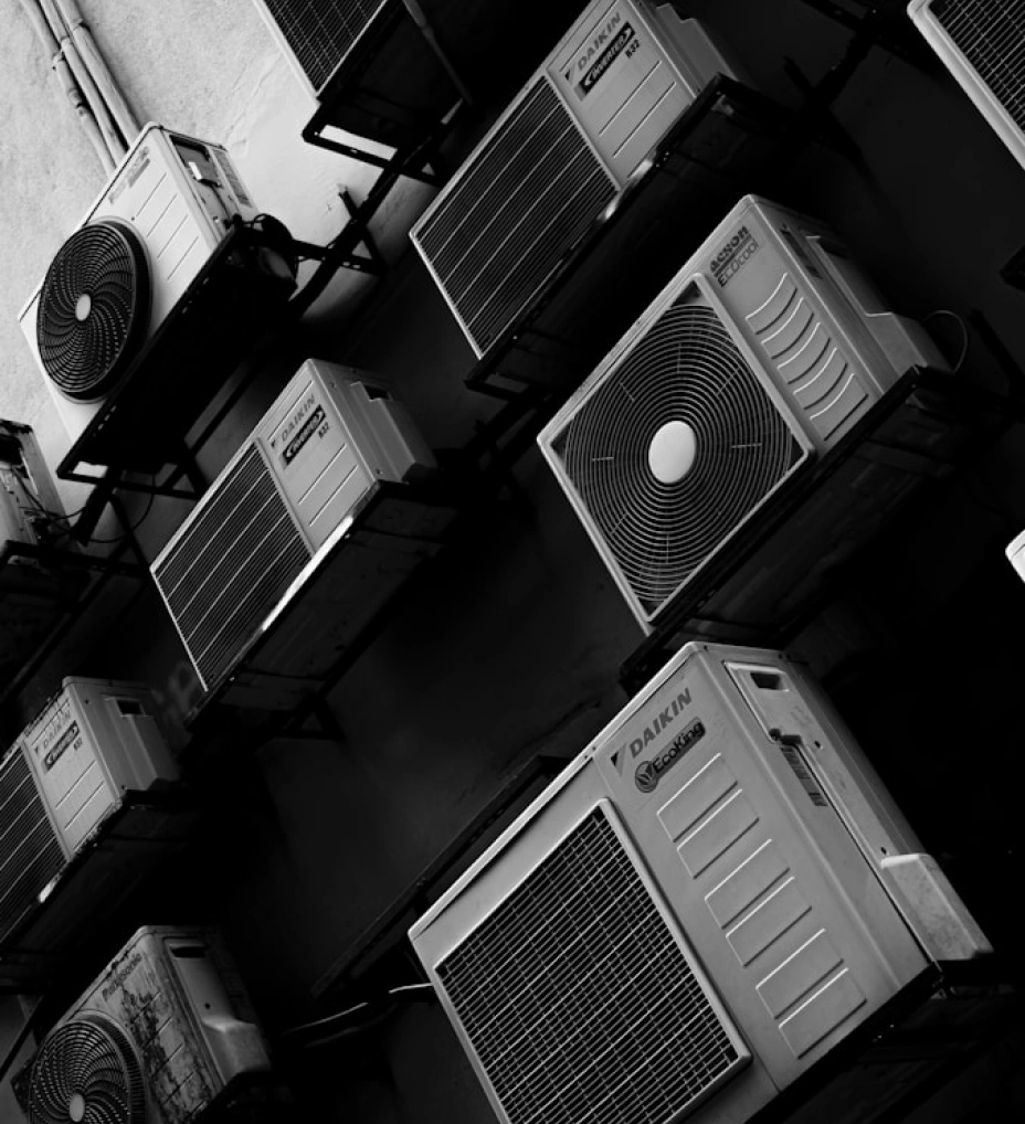 Černobílá fotografie řady venkovních klimatizačních jednotek Daikin a Acson na fasádě